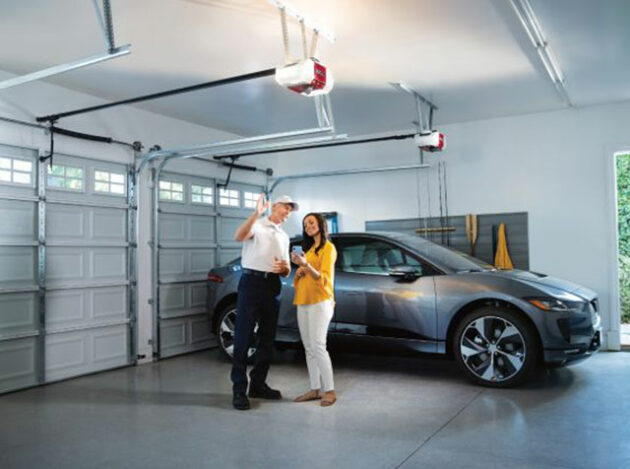This is a picture of a garage door technician pointing to a garage door opener inside a homeowner's home.