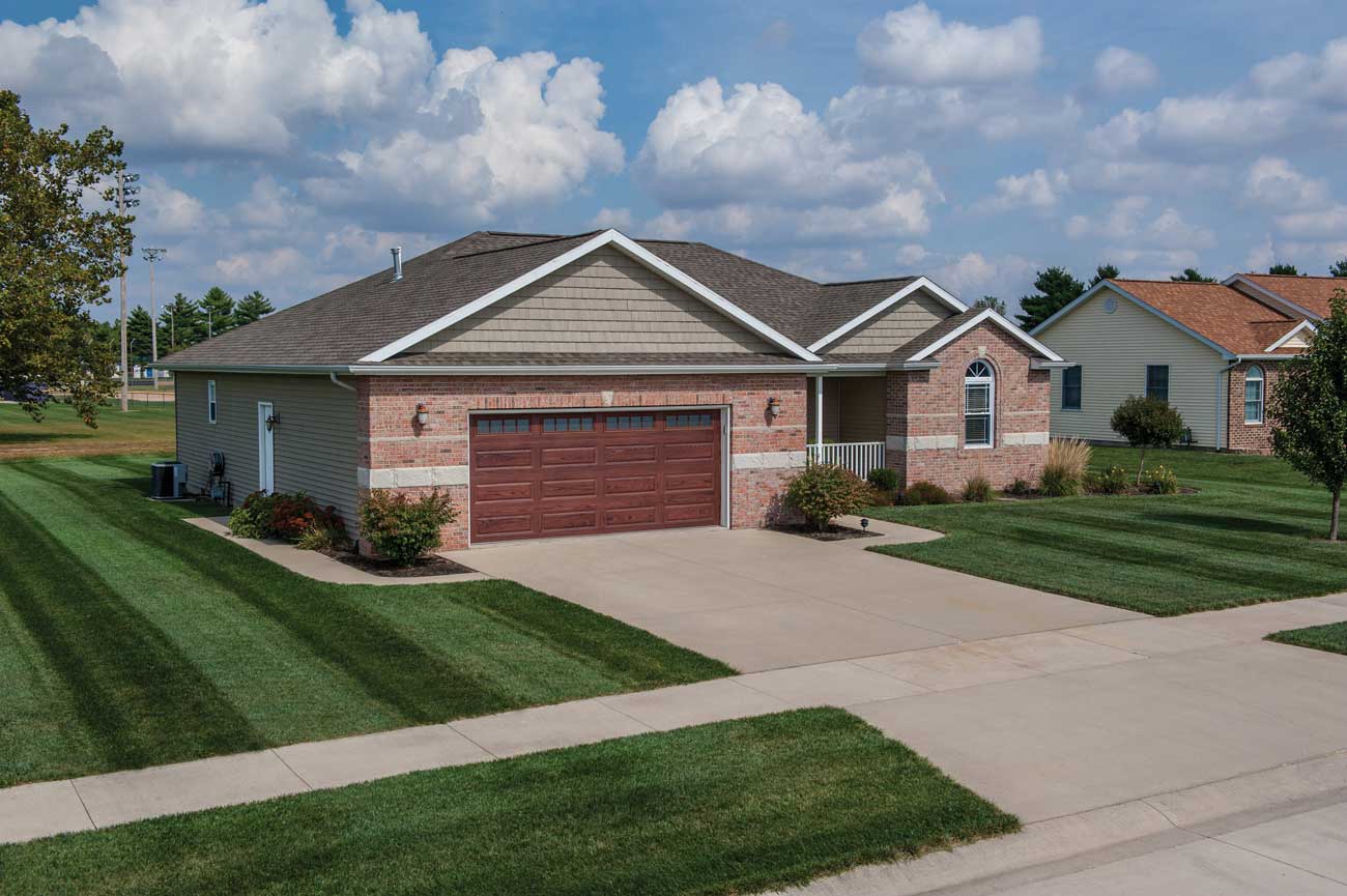 This is an image of a traditional steel garage door with windows with a woodtone finish.