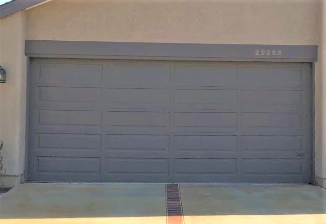 This is an image of a grey wood one piece garage door before a new install in Mission Viejo, CA.