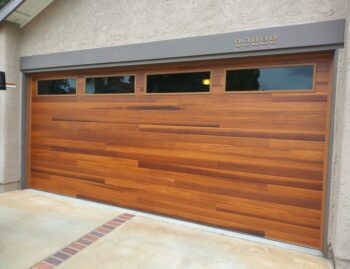 This is an image of a faux wood garage door installation in Mission Viejo, CA. It is cedar color planks design.