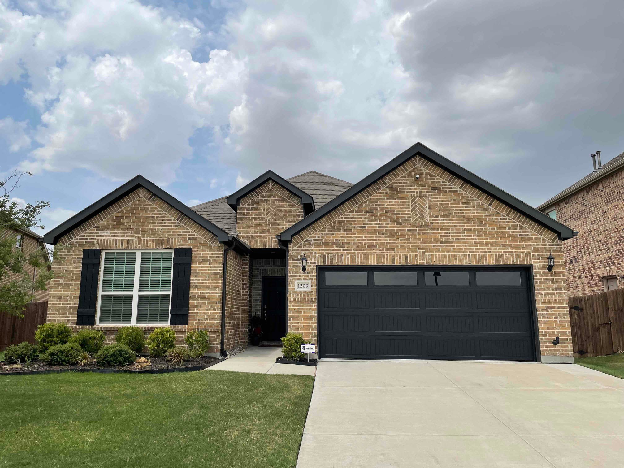 This is an image of a black garage door on a brick home.