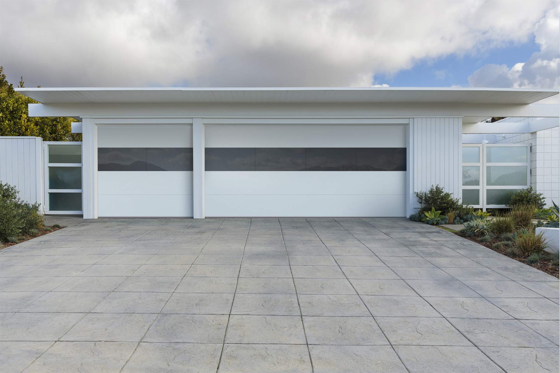 This is an image of a beach home with a white glass garage door with windows.
