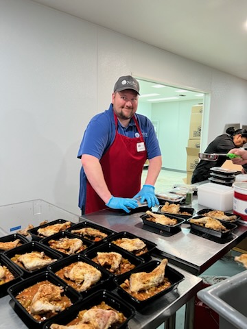 Jonathan, Entry System's General Manager, doing meal prep for OC nonprofit Bracken's Kitchen. He is in an apron with individual meal containers.