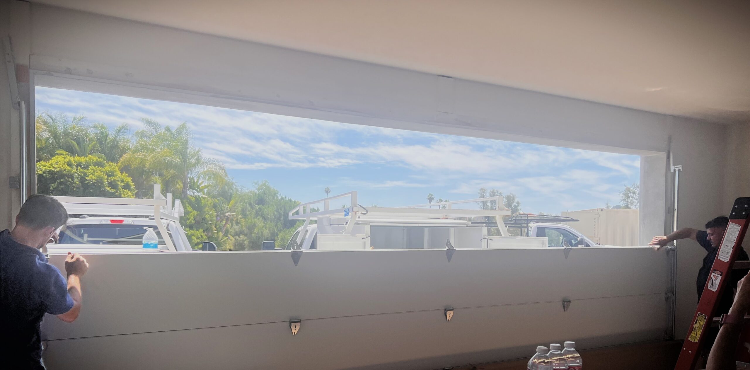 shows a garage door installation in progress with the hinges being attached and the tracks being adjusted