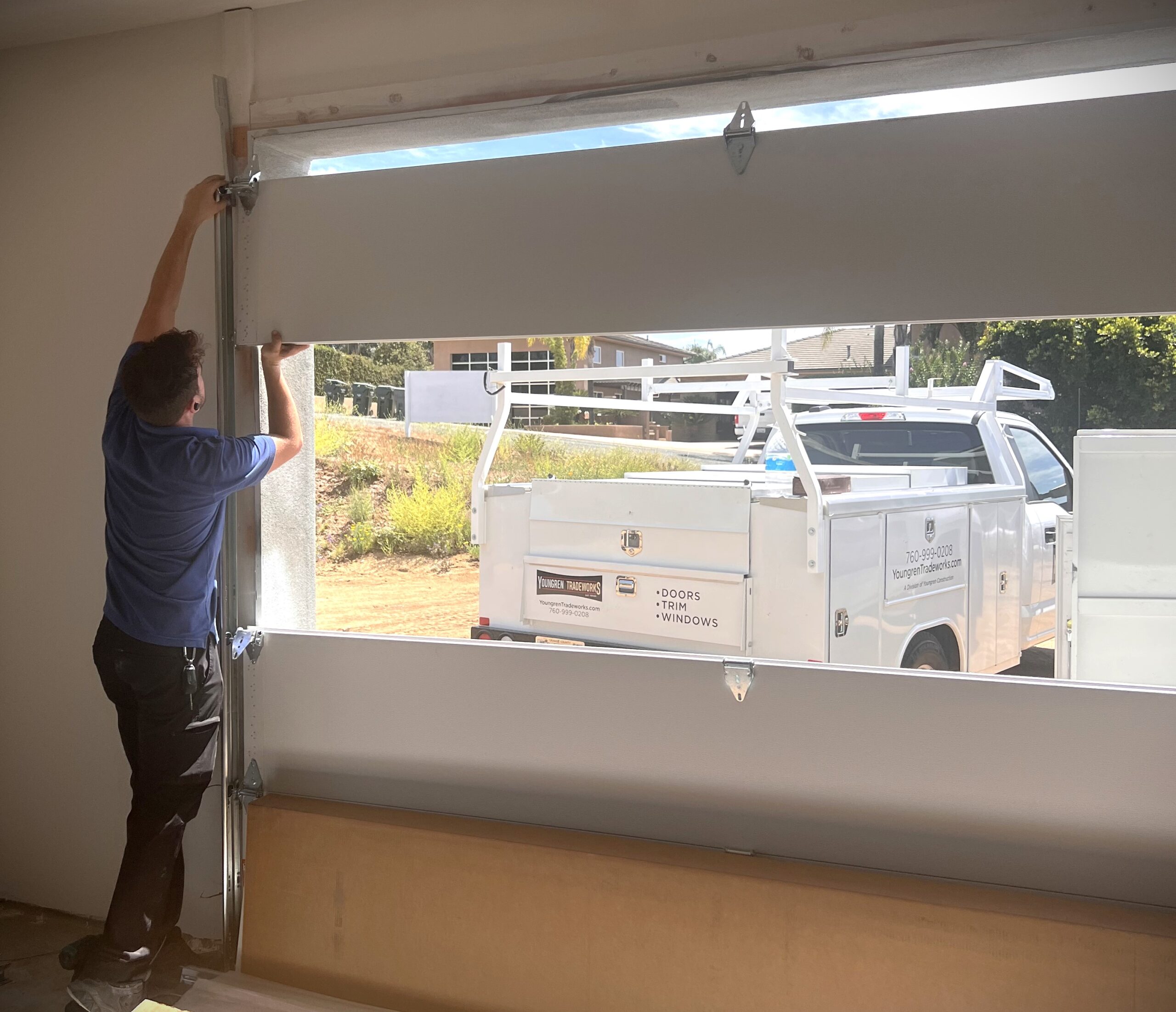 Shows garage door installers installing the third garage door section