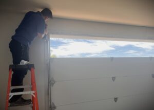 Shows a garage door installer preparing the horizontal track to install on a garage door