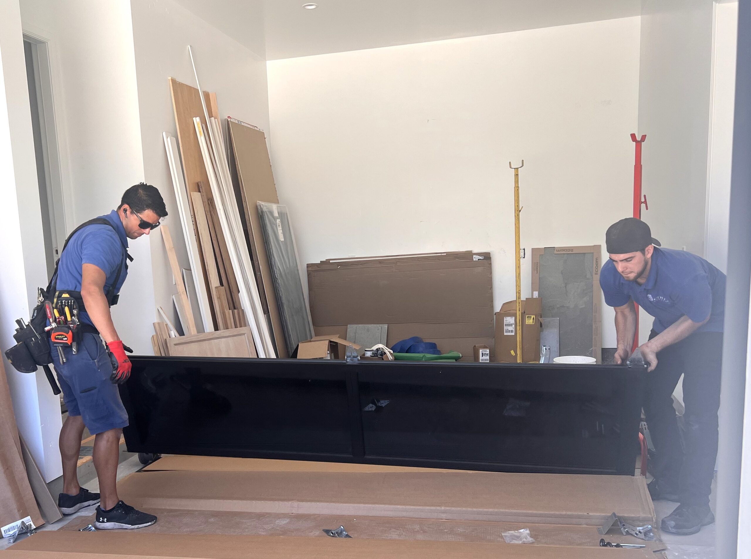 Image of garage door installers lifting black garage door section up for install.