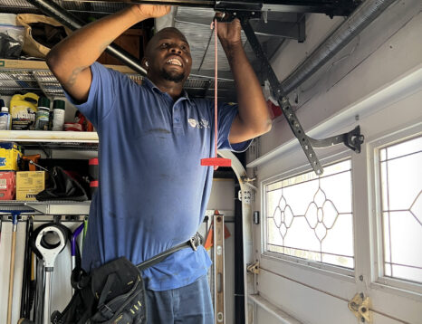 Image of garage door repair technician fixing the trolley on the rail of a garage door opener.
