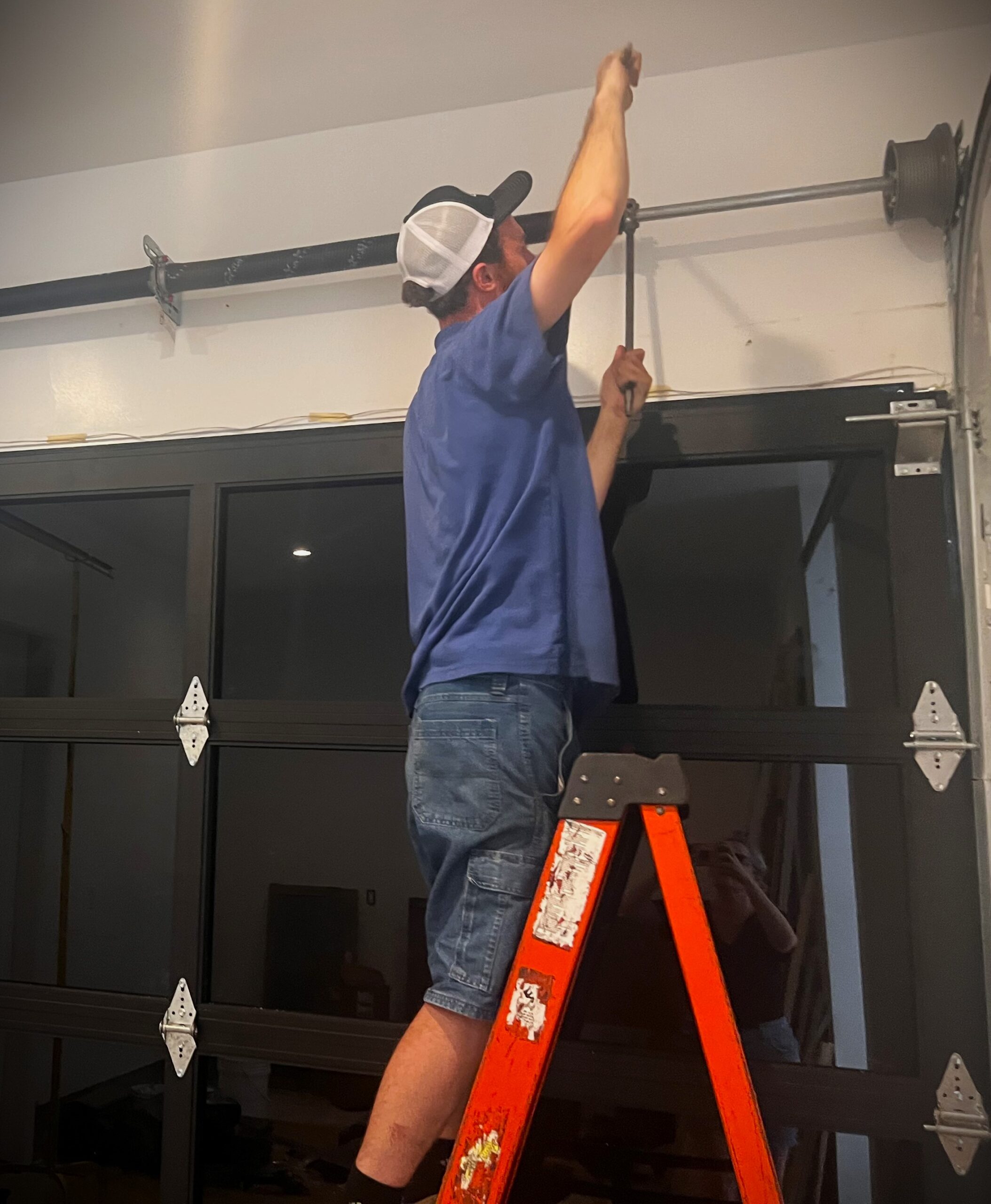 Image shows garage door tech winding new springs during installation.