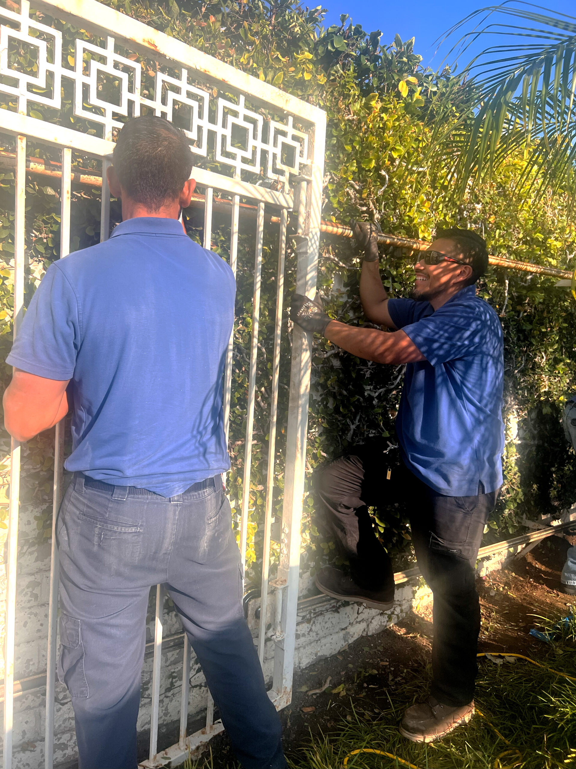 Gate technicians repairing old electric automated gate that needs maintenance.