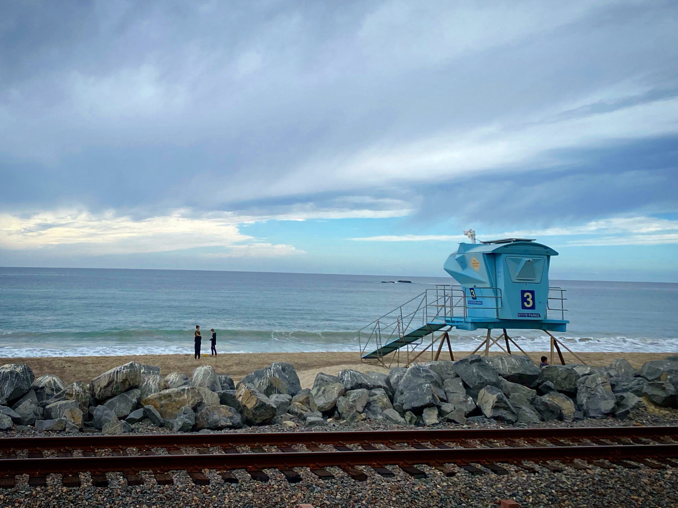blue lifeguard tower in front of railroad tracks