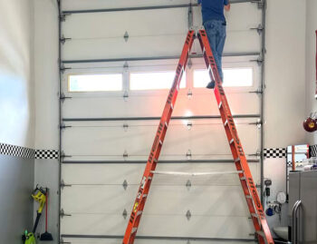 Garage door technician on ladder working on custom 16 foot garage door