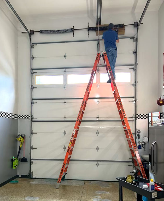 Garage door technician on ladder working on custom 16 foot garage door