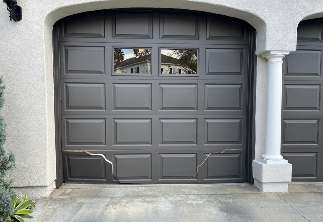 Grey garage door broken in Ladera Ranch before replacement with cracks