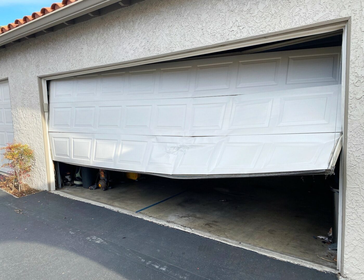 steel garage door crumpled after being hit by car in Laguna Niguel