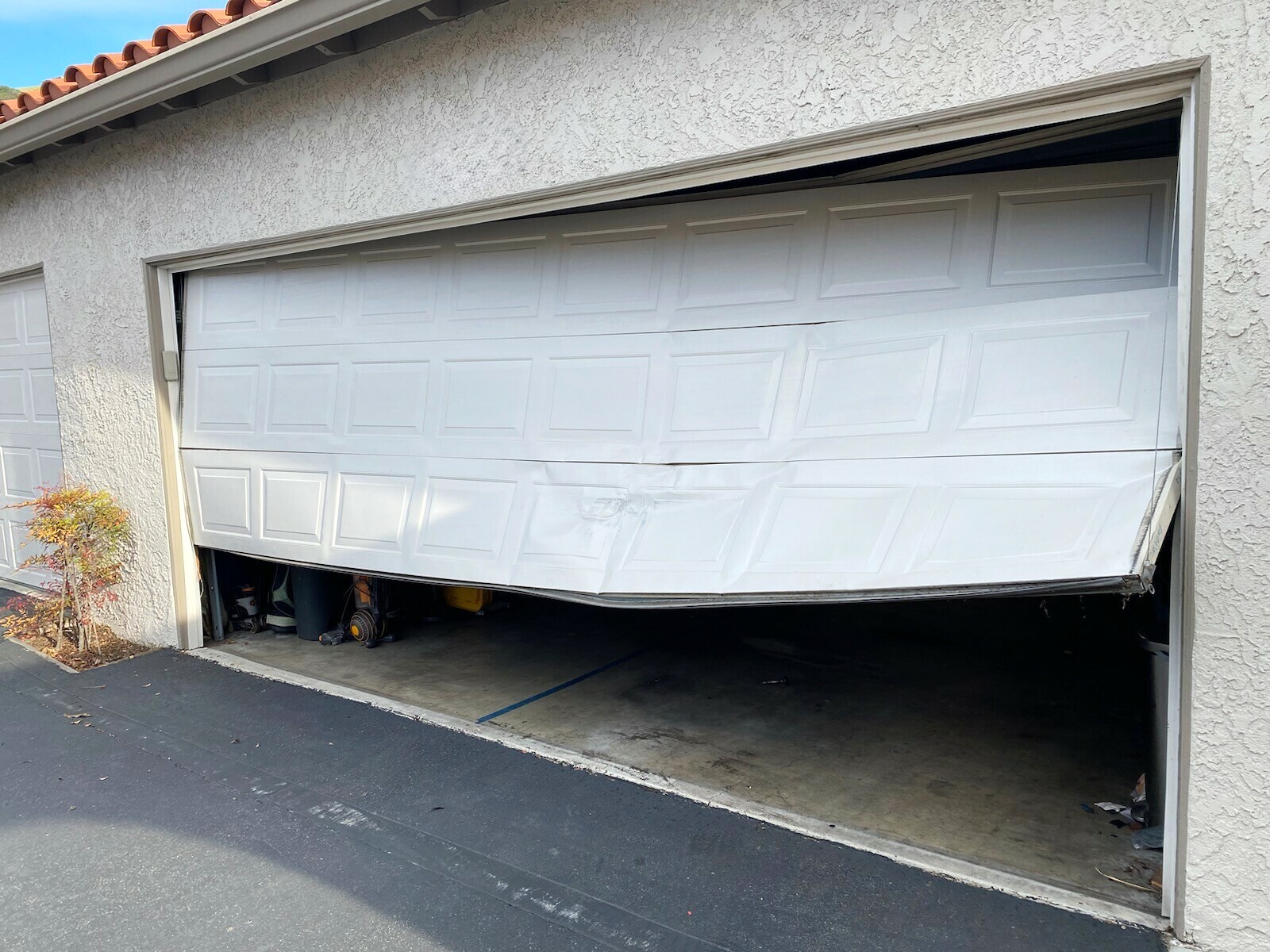 steel garage door crumpled after being hit by car in Laguna Niguel