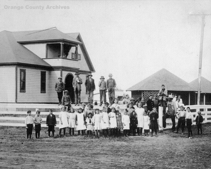 Black and white image of children standing in front of buildings.